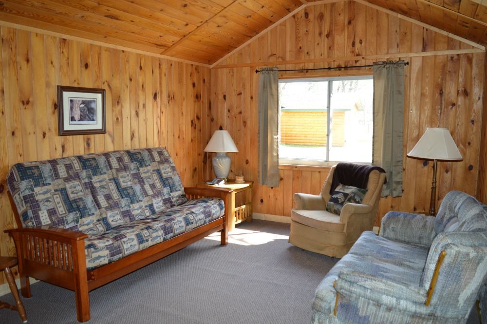 a living room with a couch, chairs, lamps and a window