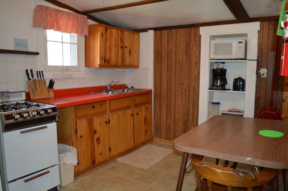 a kitchen with a stove, sink, table and chairs
