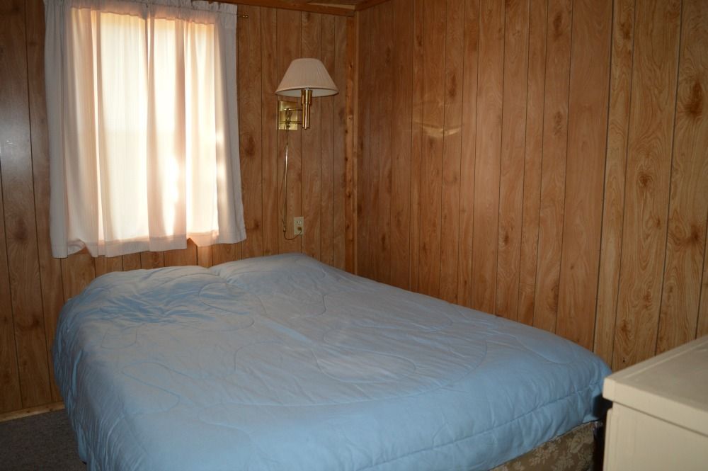 a bedroom with a bed and a window with wood paneling