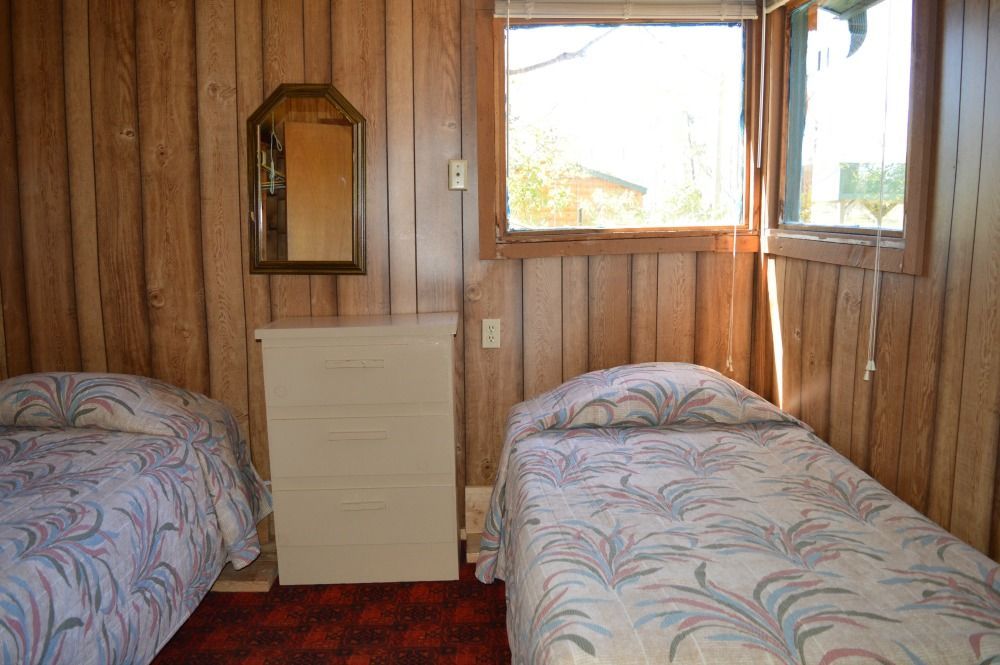 a bedroom with two beds, a dresser, a mirror and a window