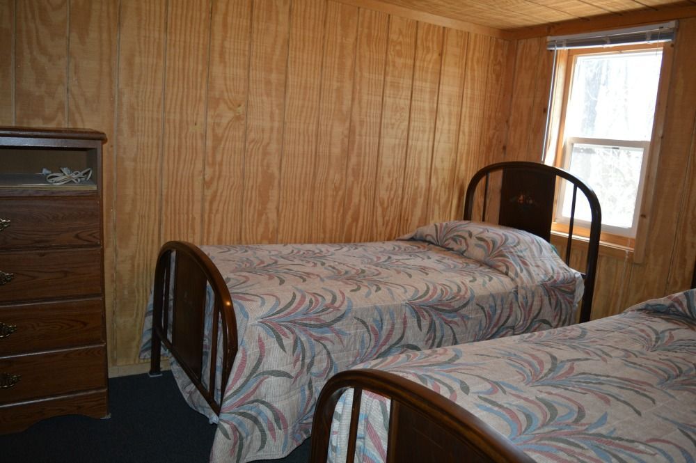 a bedroom with two twin beds, a dresser and a window