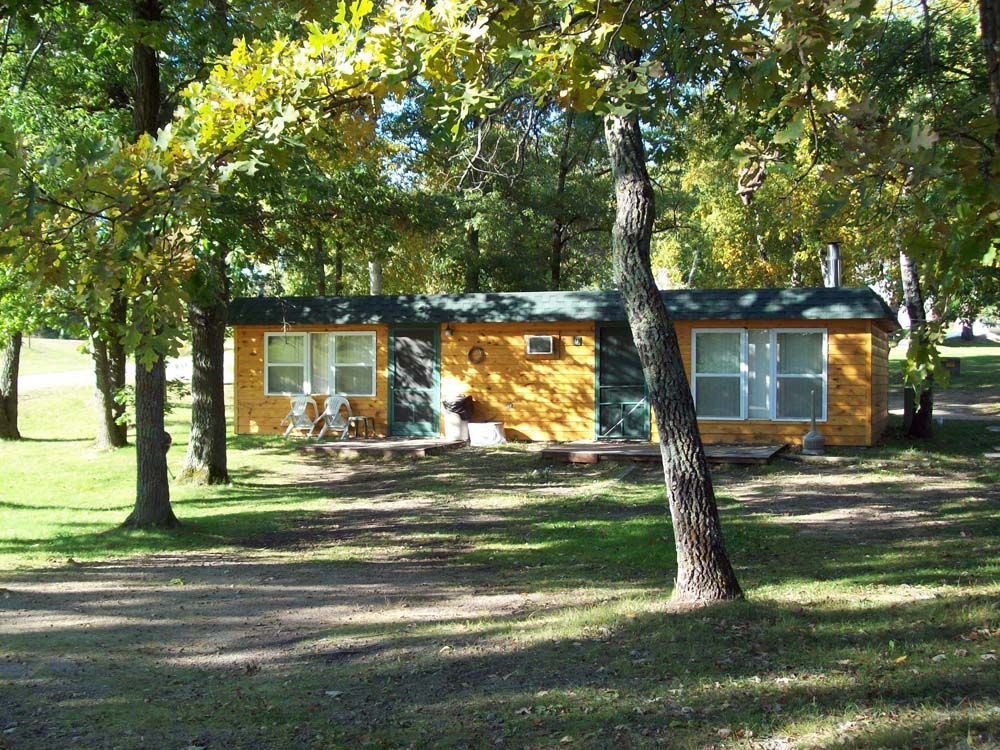 a small yellow house is surrounded by trees and grass