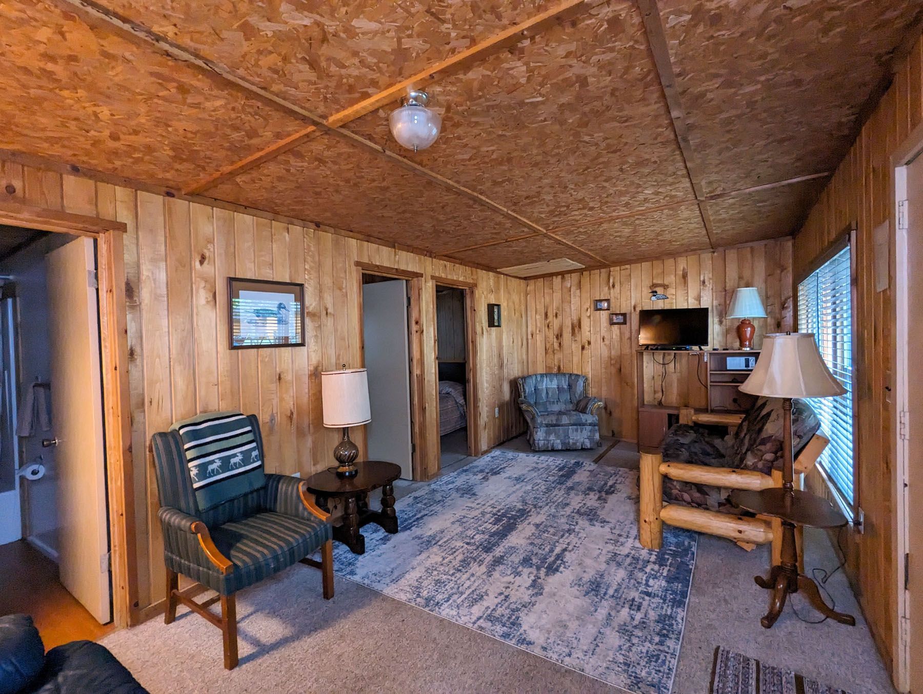 a living room with a couch, chairs, lamps and a television