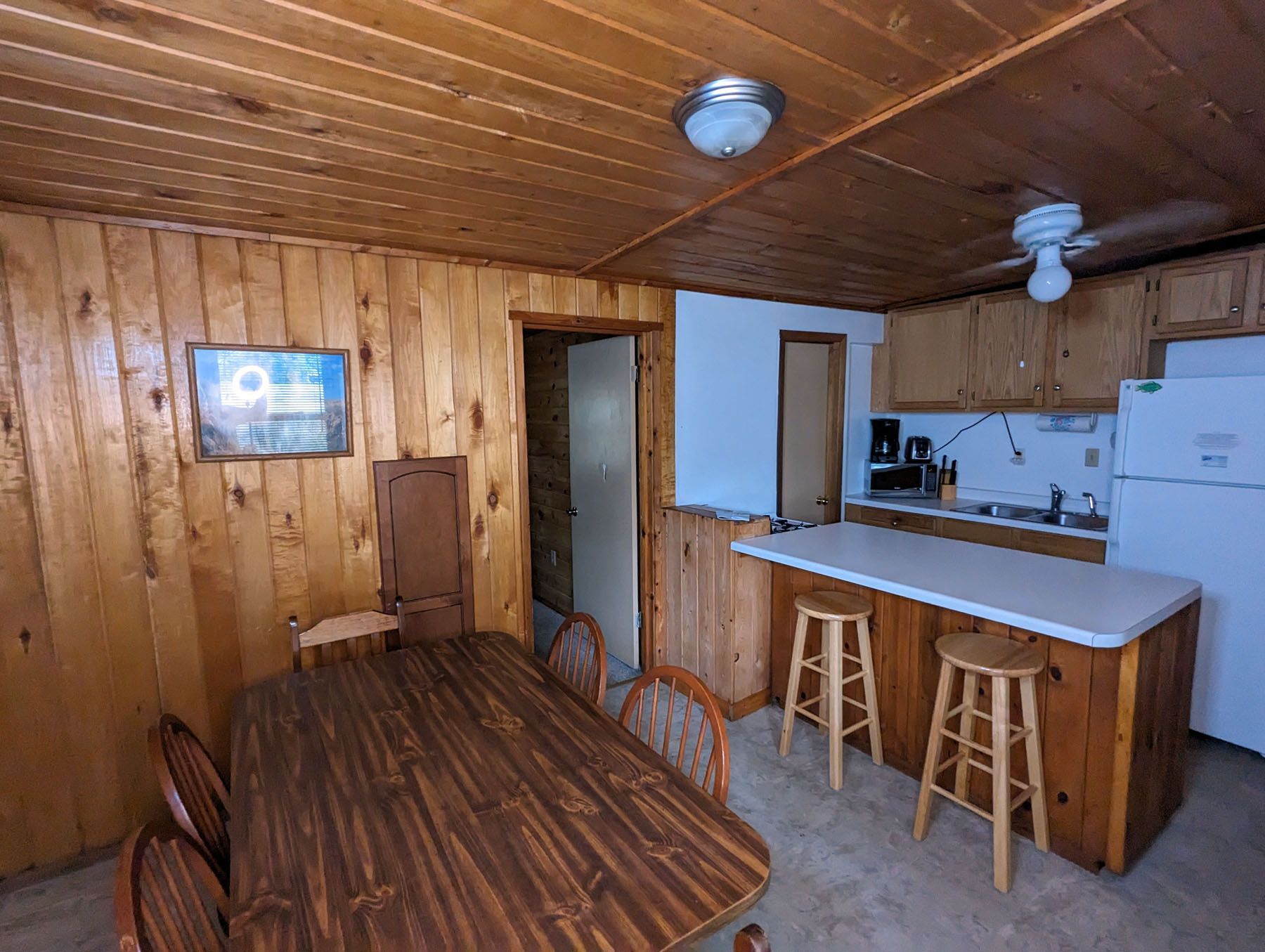 a kitchen with a table, chairs, stools and a refrigerator