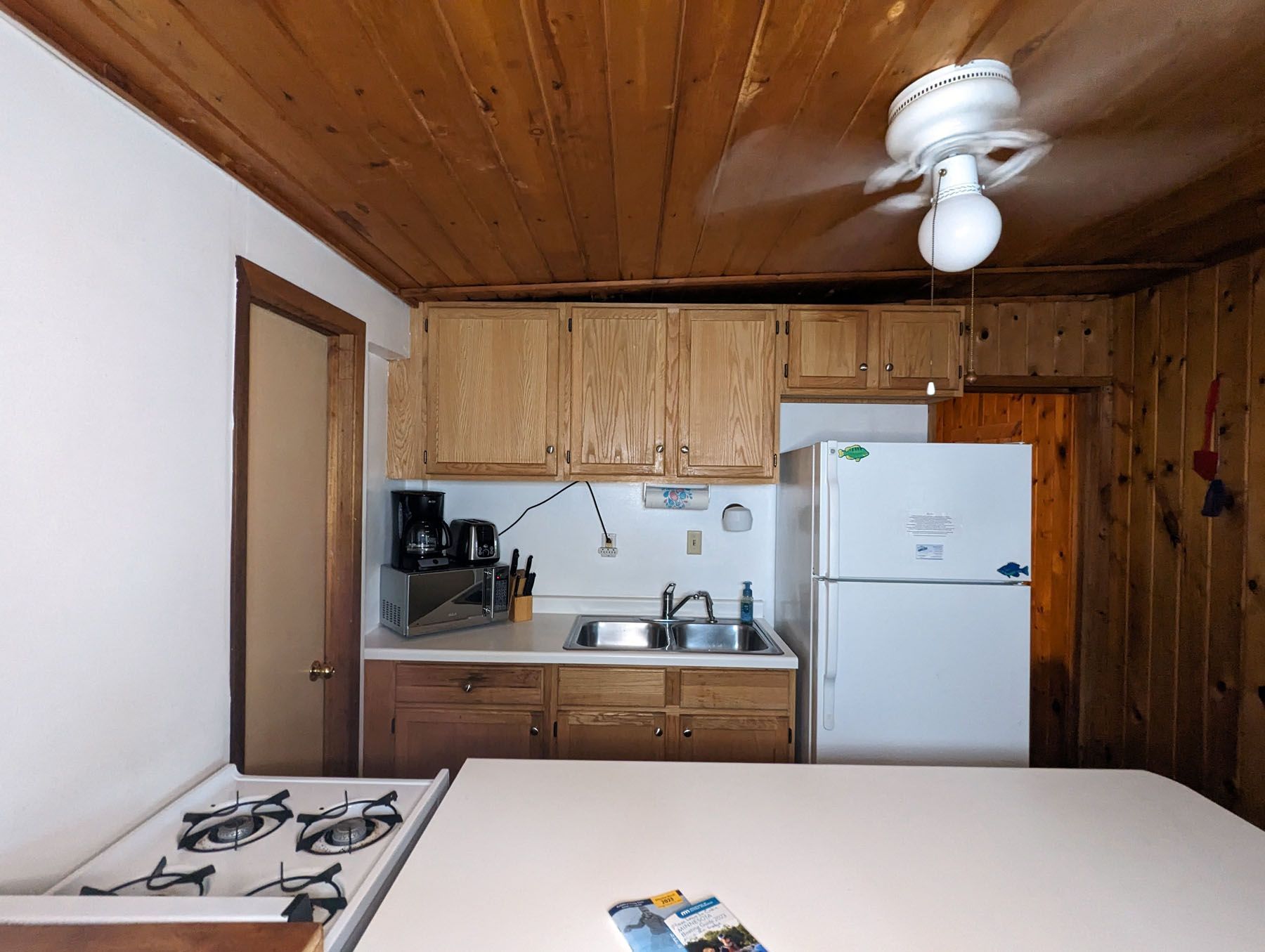 a kitchen with a stove and a refrigerator and a ceiling fan
