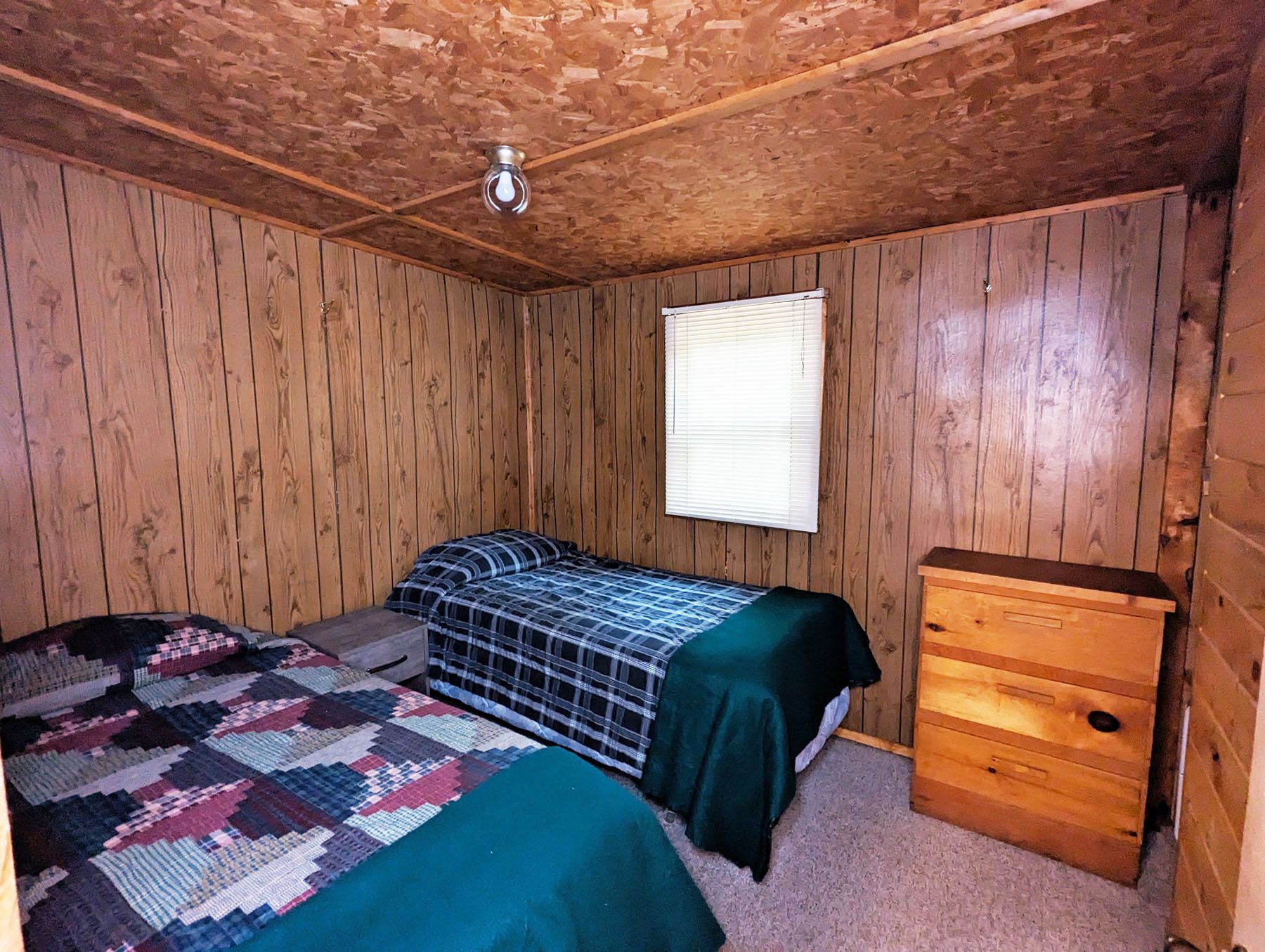 a bedroom with two beds, a dresser and a window