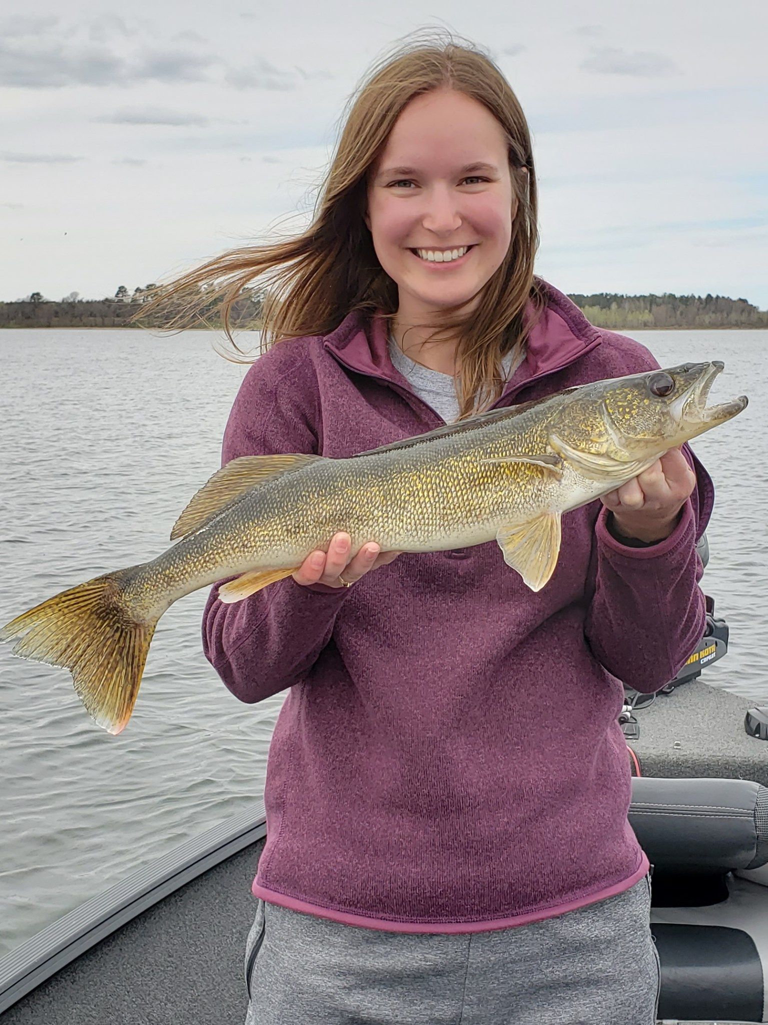 a woman is holding a large fish in her hands on a boat .
