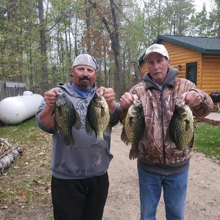 two men holding fish in front of a house