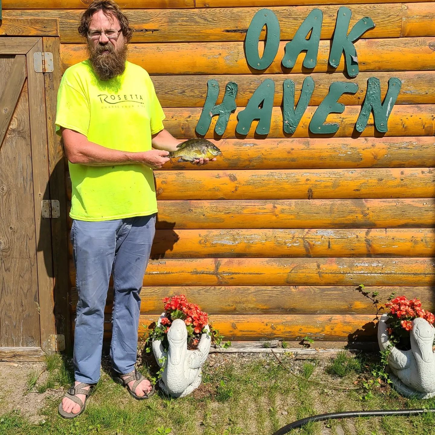 a man holding a fish in front of a sign that says oak haven