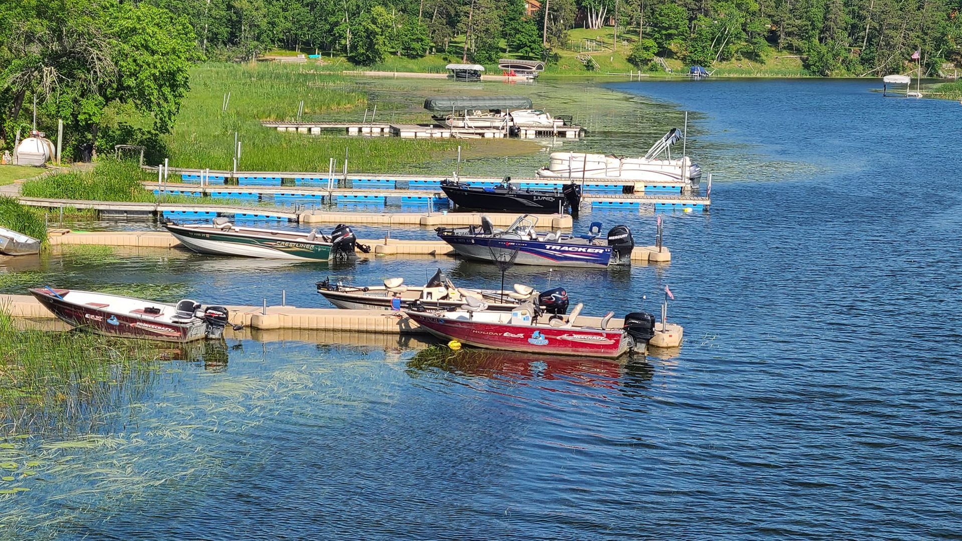 a group of boats are docked at a dock on a lake .