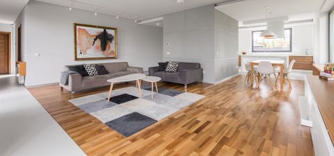 A living room with hardwood floors, a couch, a table, and chairs.