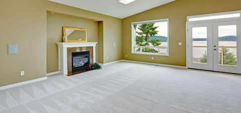 An empty living room with a fireplace and a large window