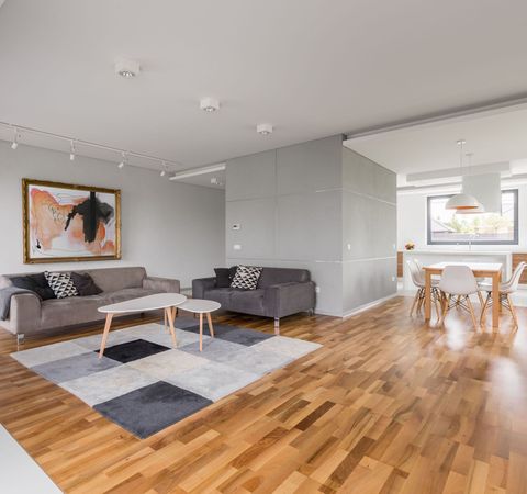 A living room with hardwood floors, a couch, a table, and chairs.