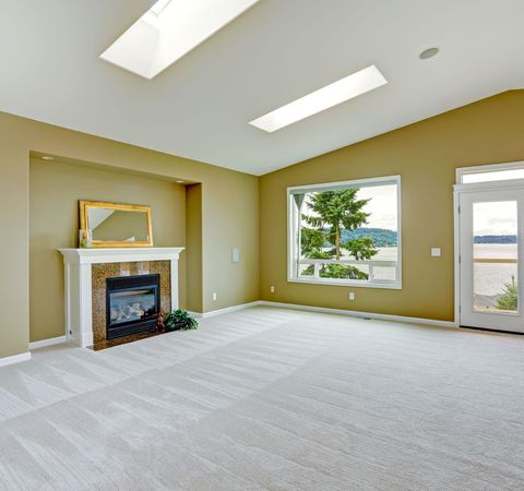 An empty living room with a fireplace and a large window