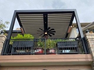 A balcony with a pergola and a ceiling fan.