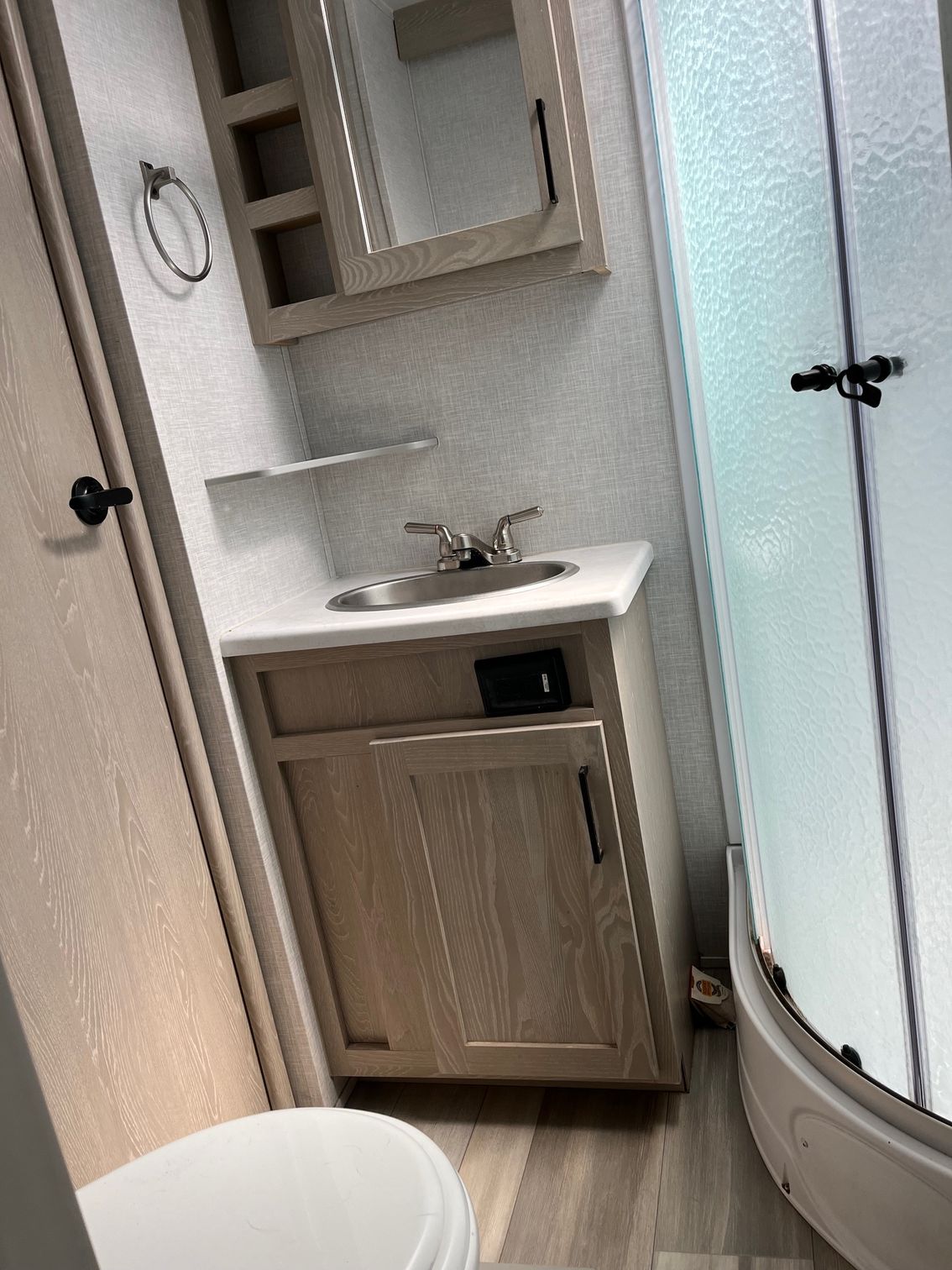 Compact bathroom with sink, mirror cabinet, and frosted glass shower door