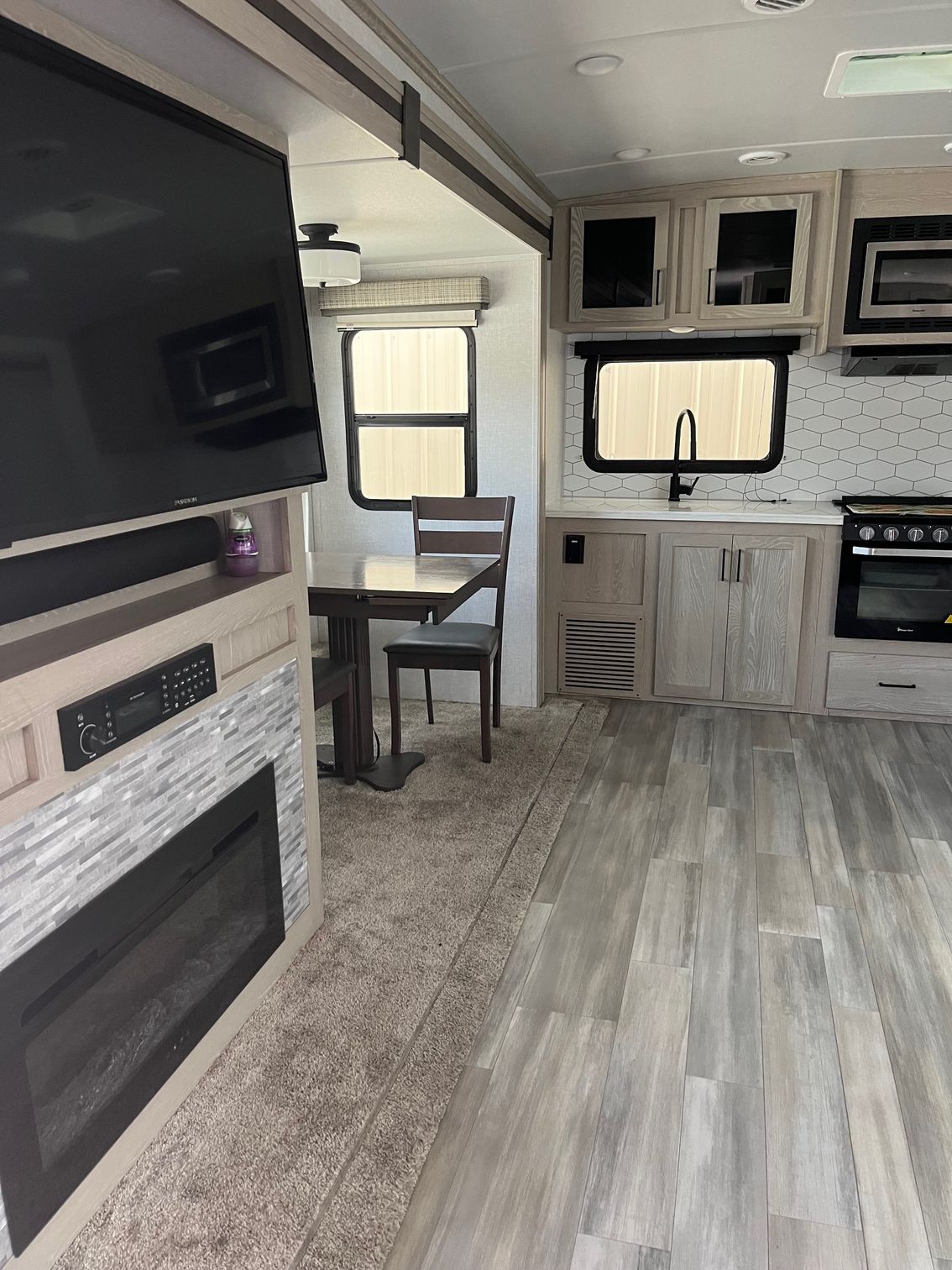 RV interior with fireplace, kitchen cabinets, dining nook, and light wood flooring