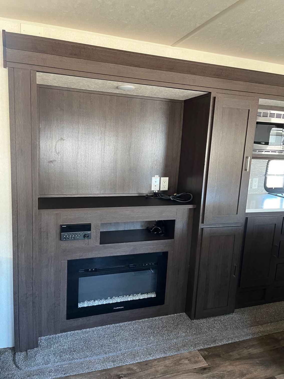 Built-in wood entertainment center with electric fireplace and shelves in a living room.