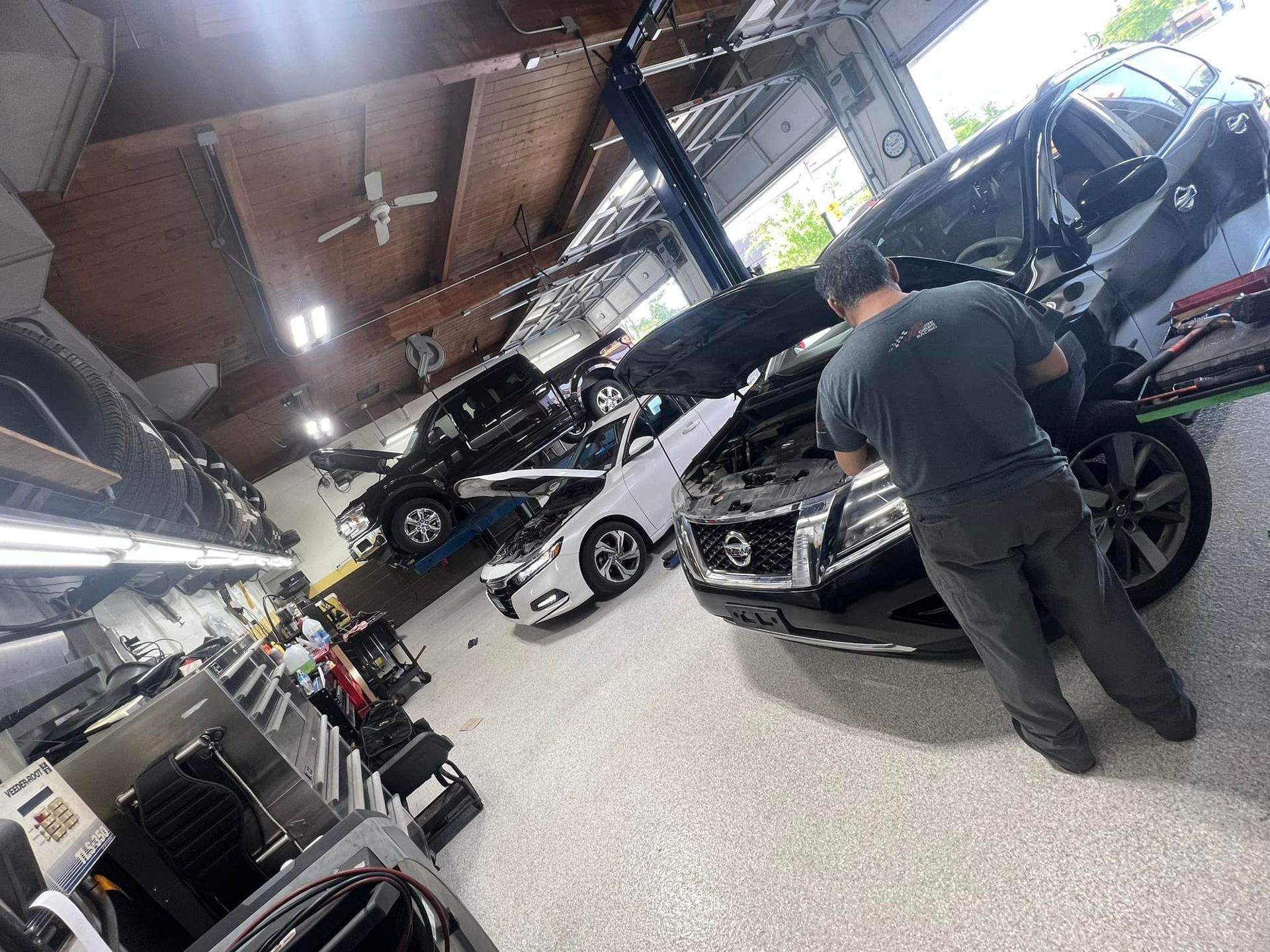 Indoor auto showroom with several cars on display and a person standing beside a dark SUV