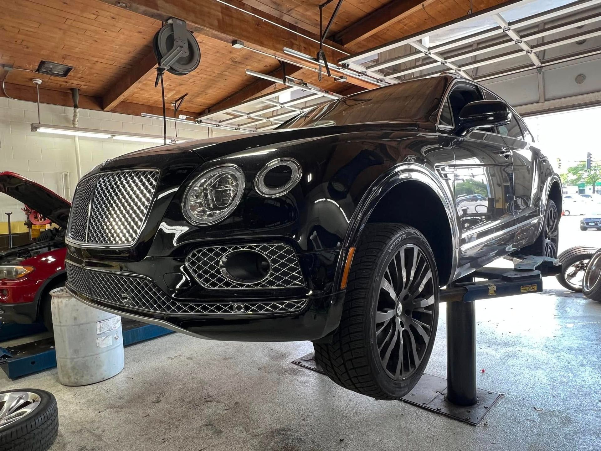 Black luxury SUV on a lift in a garage, front view with chrome grille and headlights exposed