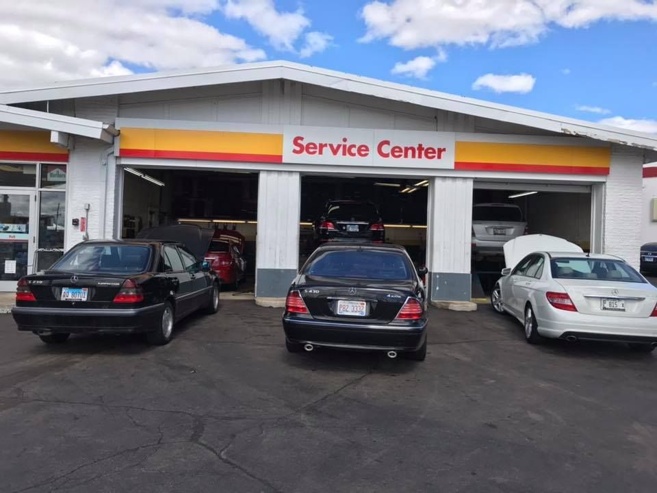 Service center with three parked cars under a white canopy
