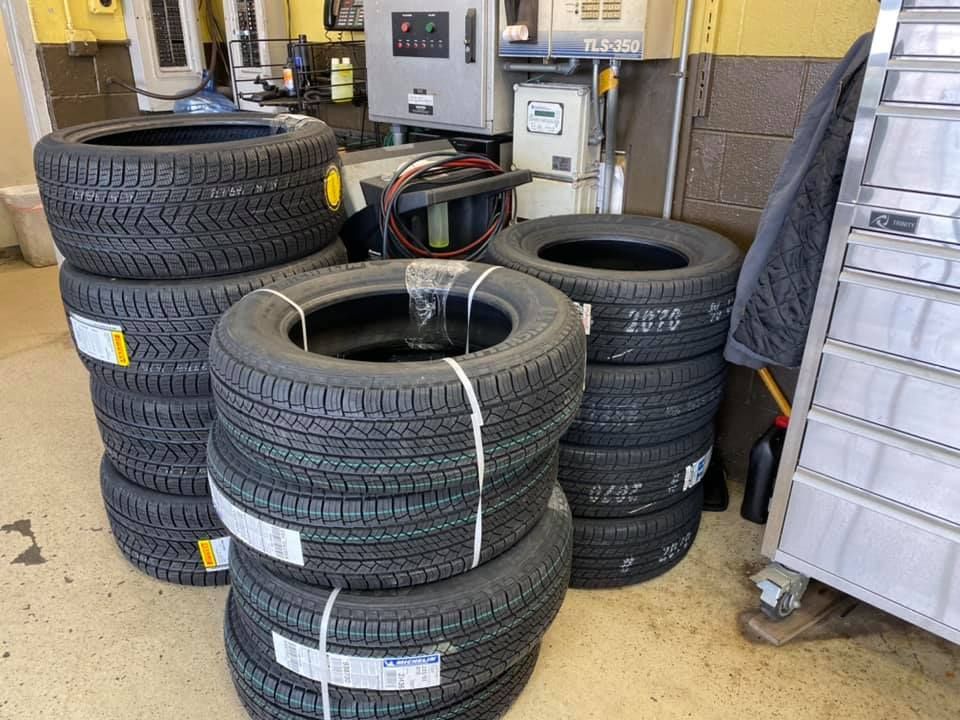 Stacks of used car tires in a workshop garage beside equipment and a display rack