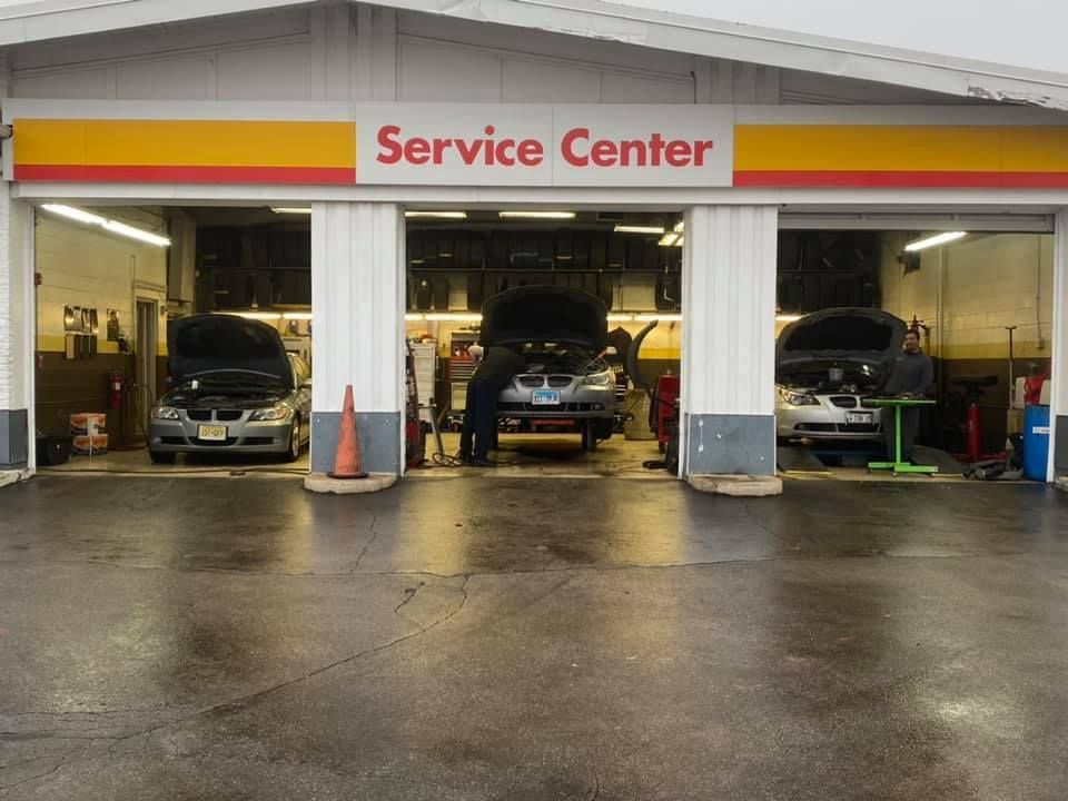 Auto service center garage with three cars under repair and cones near the entrance