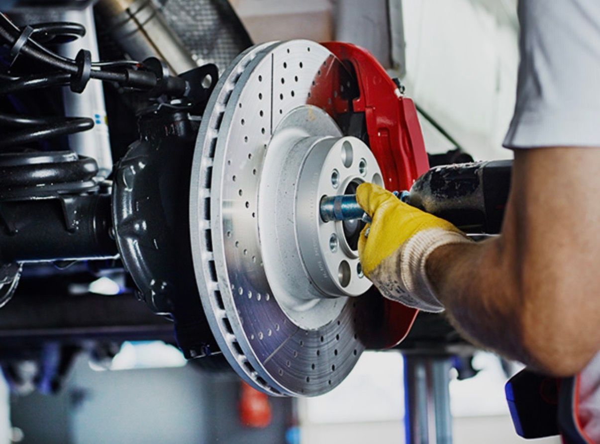 Mechanic using a wrench to install a silver brake rotor on a car wheel hub