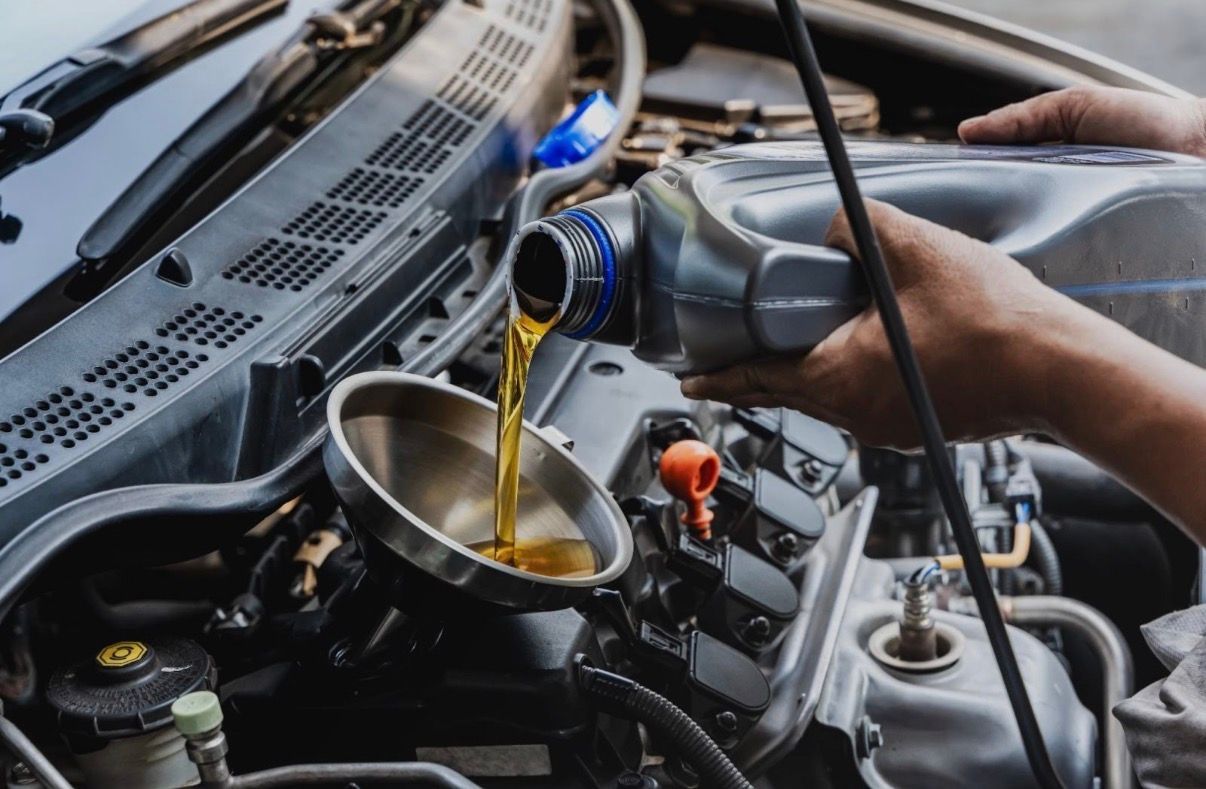 Pouring motor oil into a car engine with a funnel under the hood