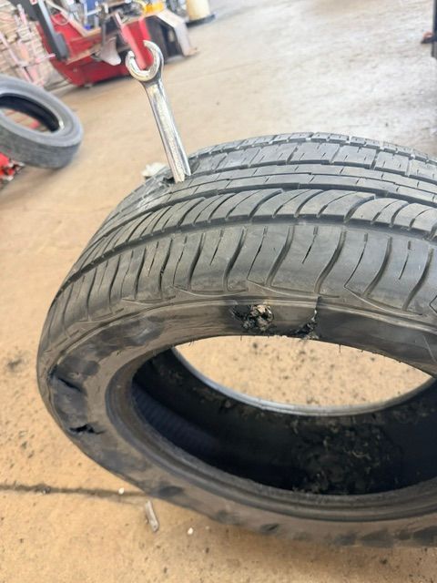 Damaged tire with a large sidewall tear in a garage or tire shop