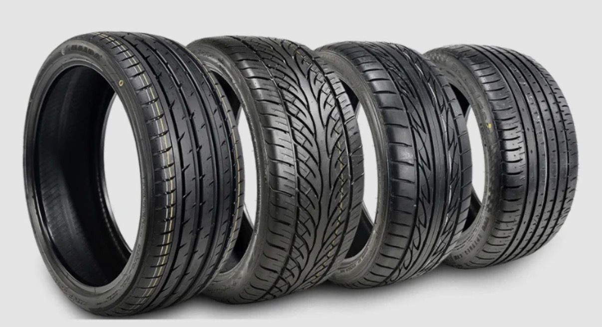 Five black car tires arranged in a row on a white background