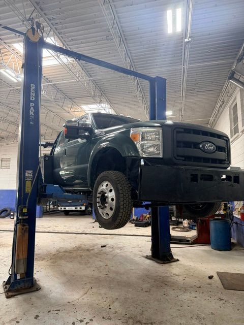 Pickup truck lifted on a blue vehicle hoist in an auto repair shop, front view