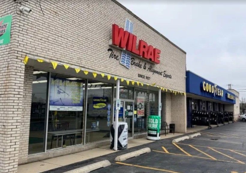 Strip mall storefronts, including Wilrae and Compare Foods, with empty parking spaces in front.