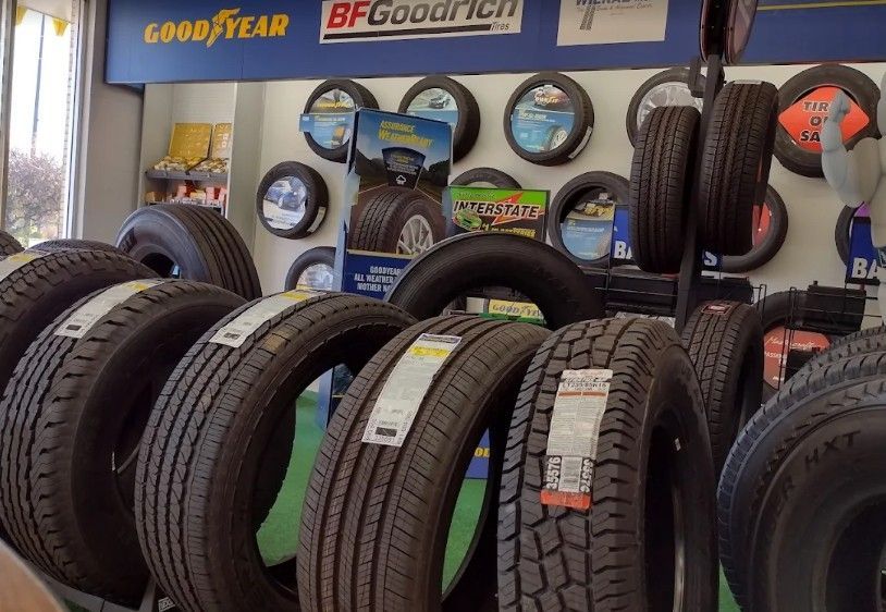 Tire shop display with rows of black tires and Goodyear and BFGoodrich signs on the wall