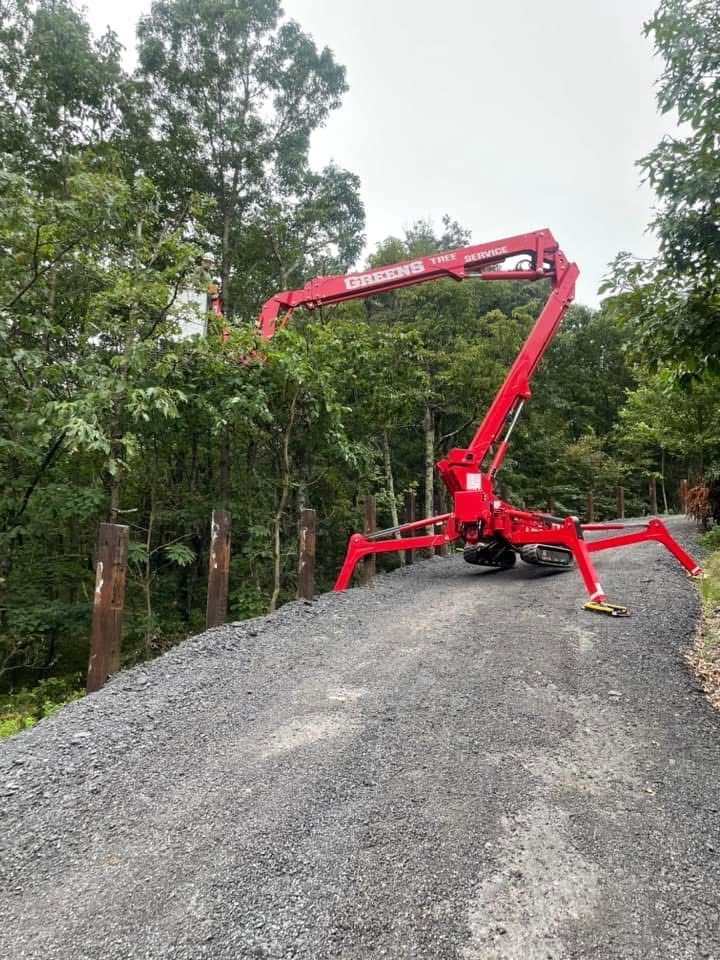 Red boom lift trimming trees on a gravel road, in a wooded area.