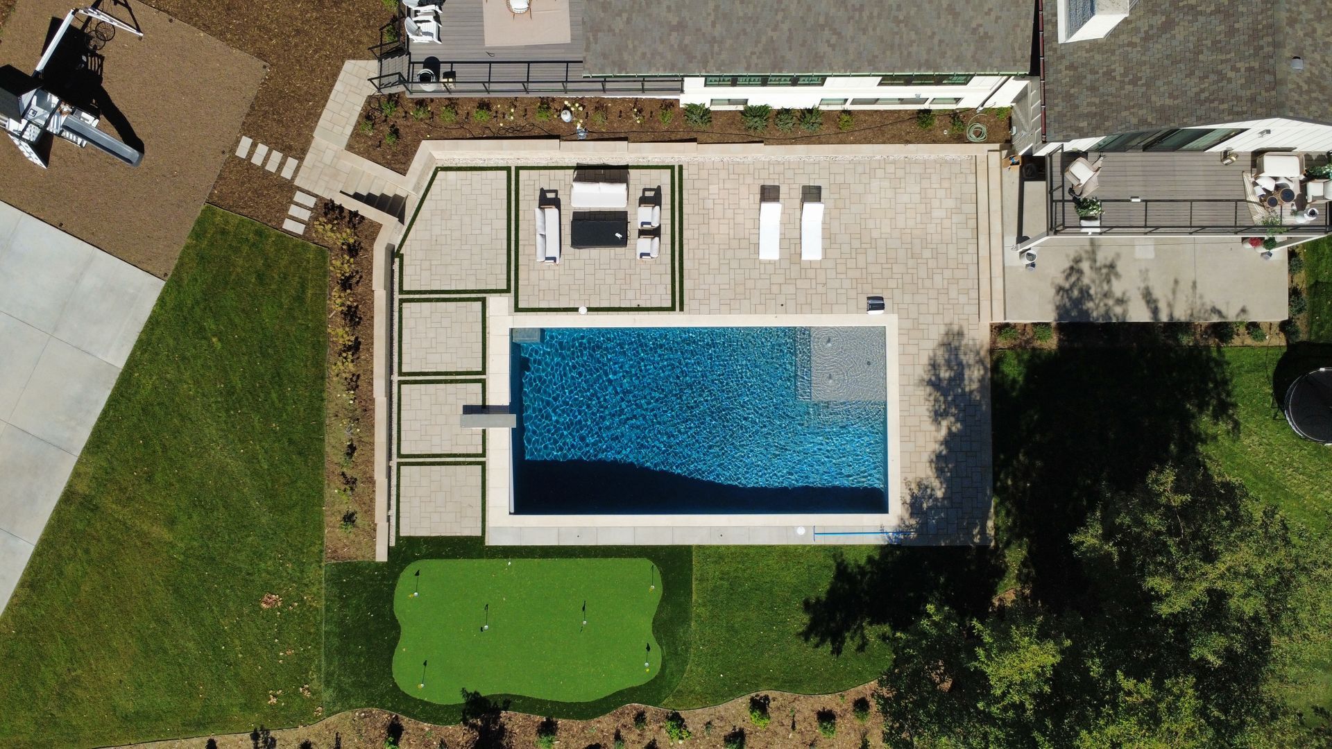 Overhead view of luxury home with pool, patio, putting green, and private jet.