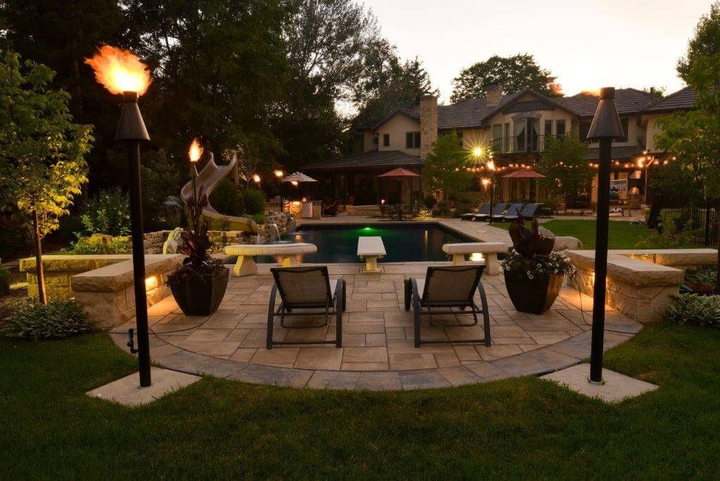Two lounge chairs are sitting on a patio in front of a large house