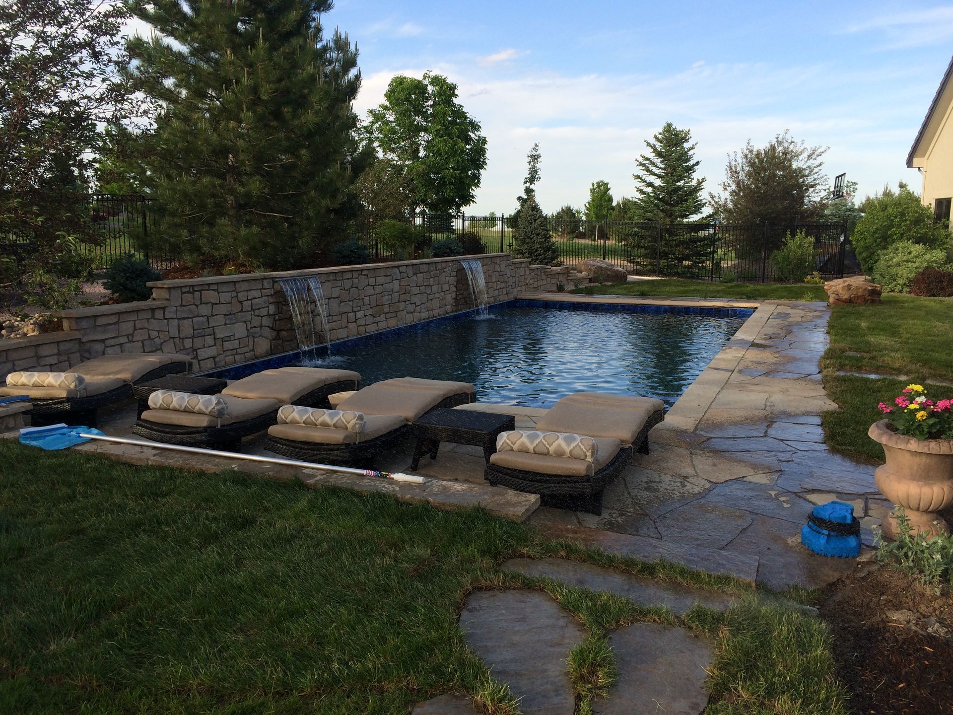 A large swimming pool with a waterfall in the backyard
