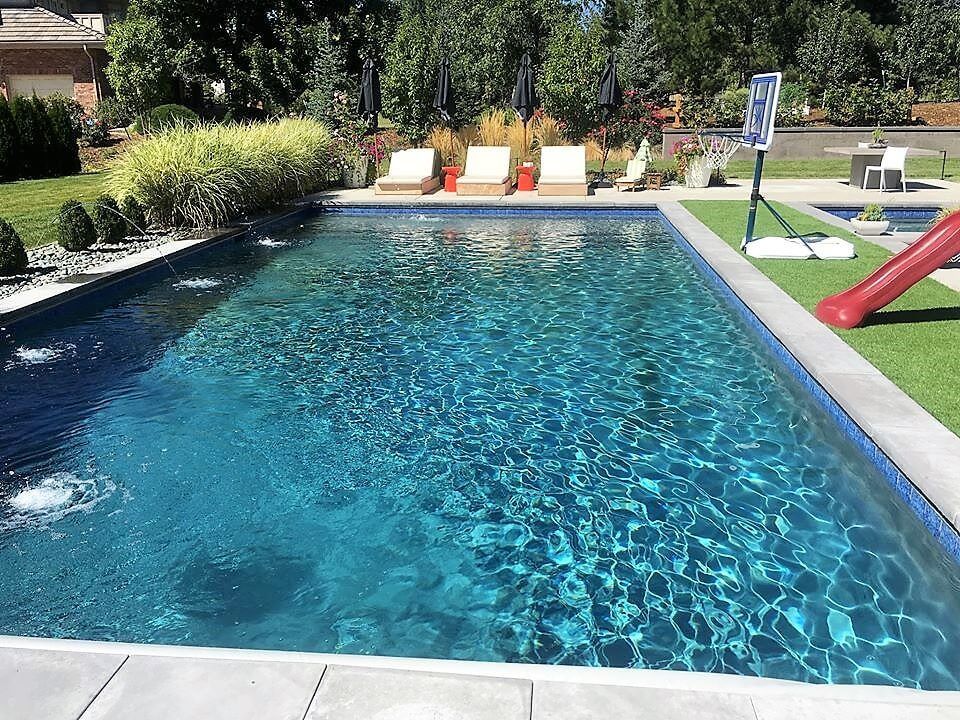 A large swimming pool with a slide in the backyard.