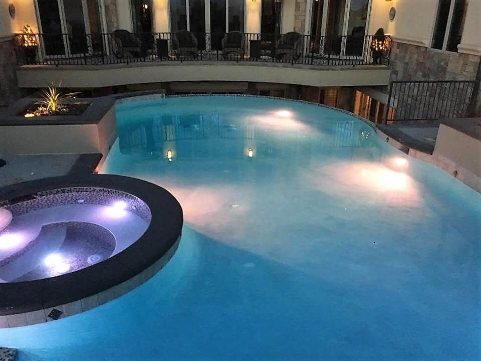 A large swimming pool with a hot tub in the middle of it.