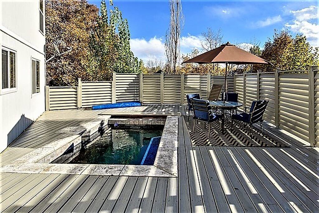A large deck with a swimming pool and a table and chairs.