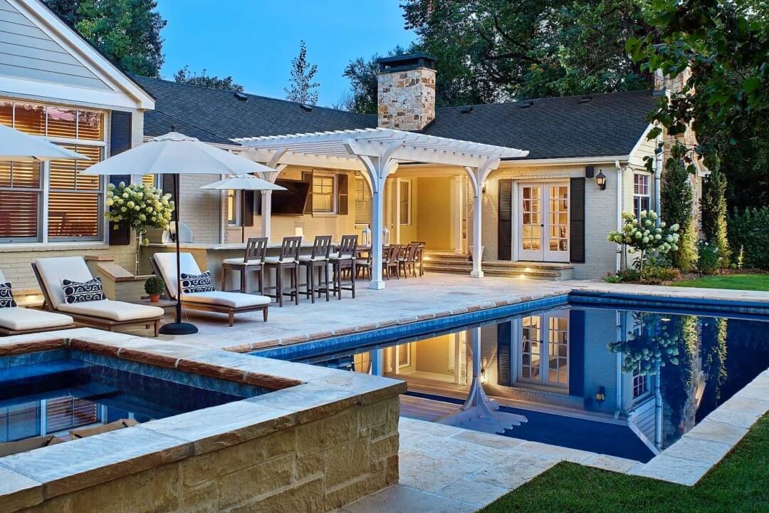 A large swimming pool is in the backyard of a house.