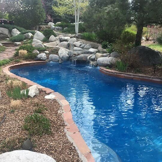 A large swimming pool surrounded by rocks and trees.