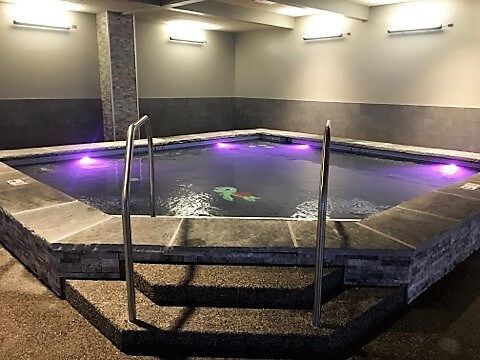 A large swimming pool with purple lights and stairs leading to it.