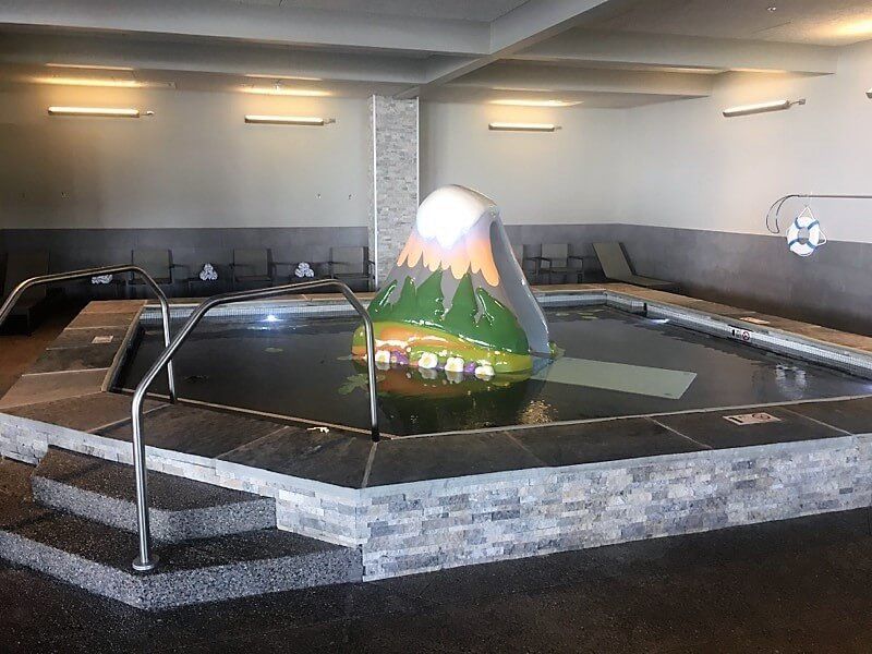 A large indoor swimming pool with a large inflatable volcano in the middle.
