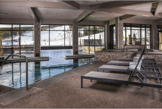 A large indoor swimming pool with a lot of windows.