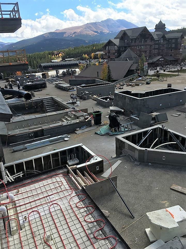 An aerial view of a building under construction with mountains in the background.