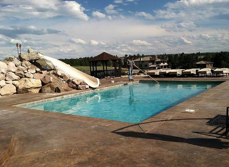 A large swimming pool with a water slide in the background.