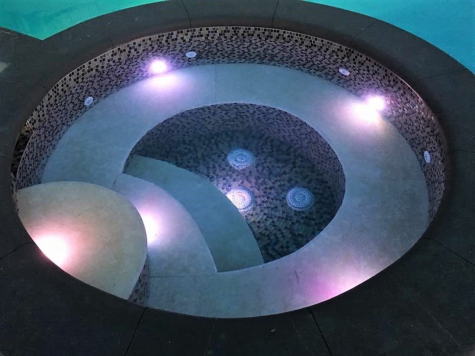 A circular pool with purple lights in it.