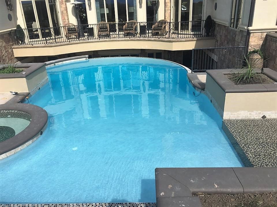 A large swimming pool with a large house in the background.